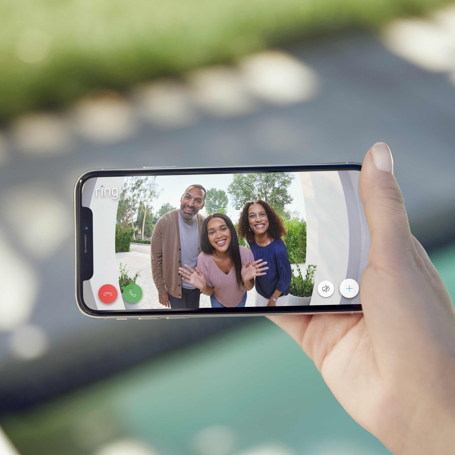 Wired Doorbell Plus (Video Doorbell Pro) (for Certified Refurbished) - Close-up of hand holding smartphone. Screen shows video of 3 smiling people looking directly into camera, taken by Video Doorbell Pro.