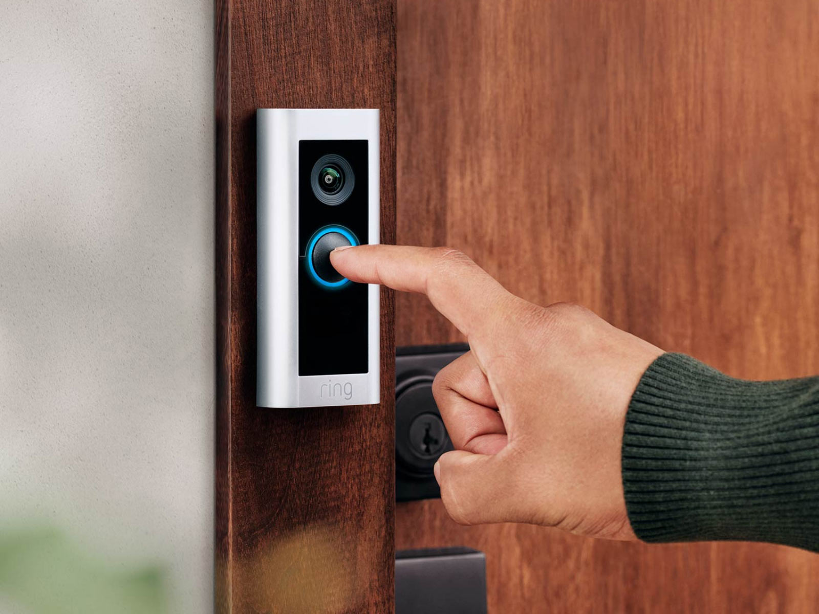 A hand pressing a Ring Wired Pro doorbell
