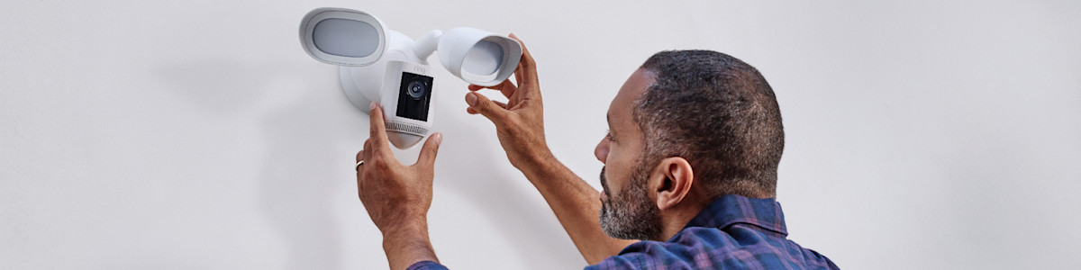 A homeowner installing their new camera outside above their garage